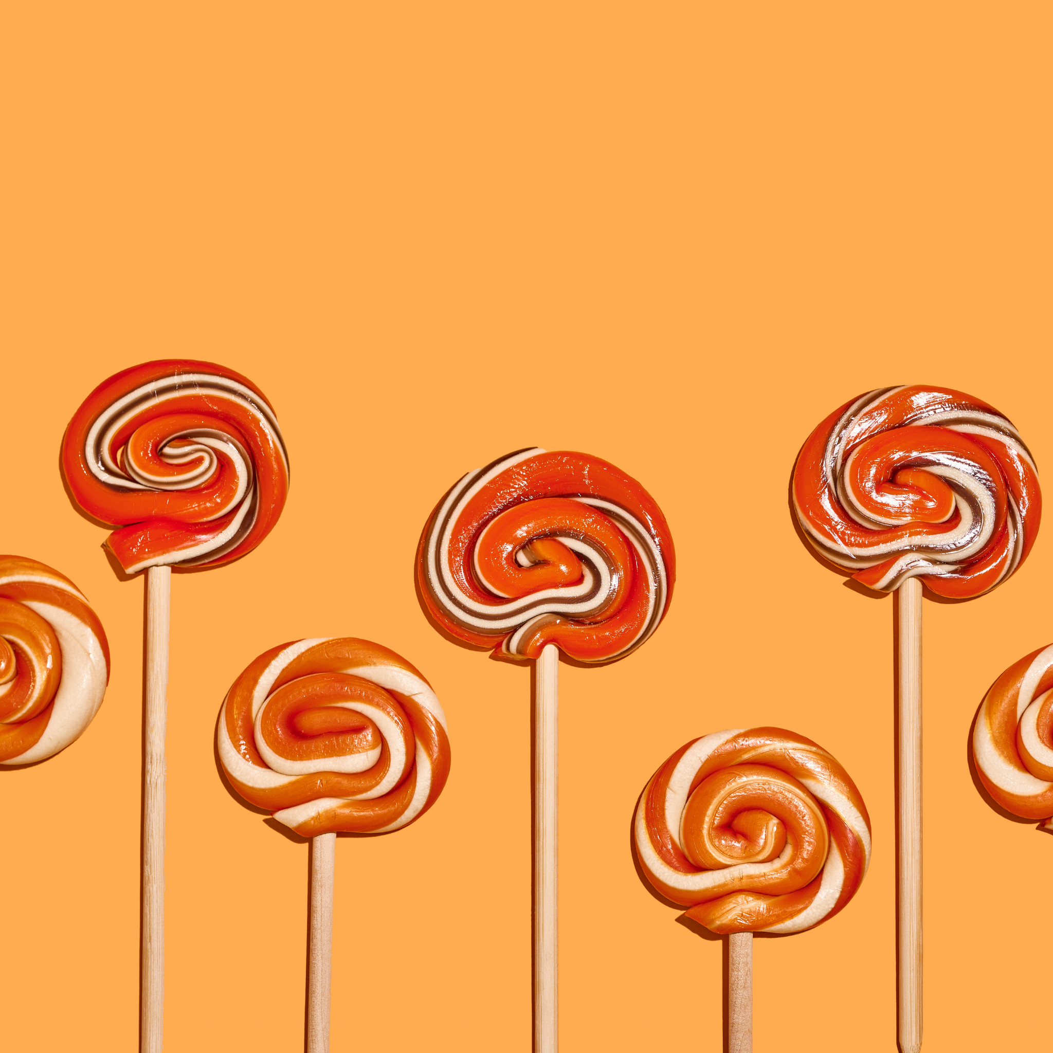 Cherry Cola lollipops on orange background