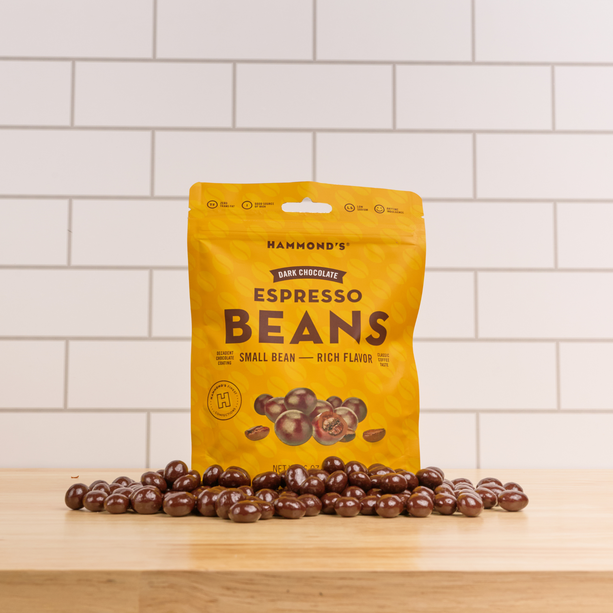 espresso beans lie on counter in front of subway tile and counter.