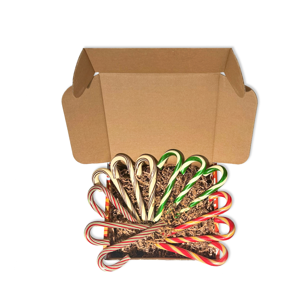 A set of festive candy canes arranged in a fan shape inside a brown kraft gift box with shredded filler, with an open matching brown box behind them, on a plain white background.