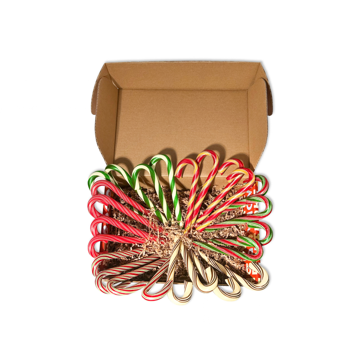 An open brown cardboard box filled with assorted candy canes in red, green, white, and gold, arranged on a plain white background.