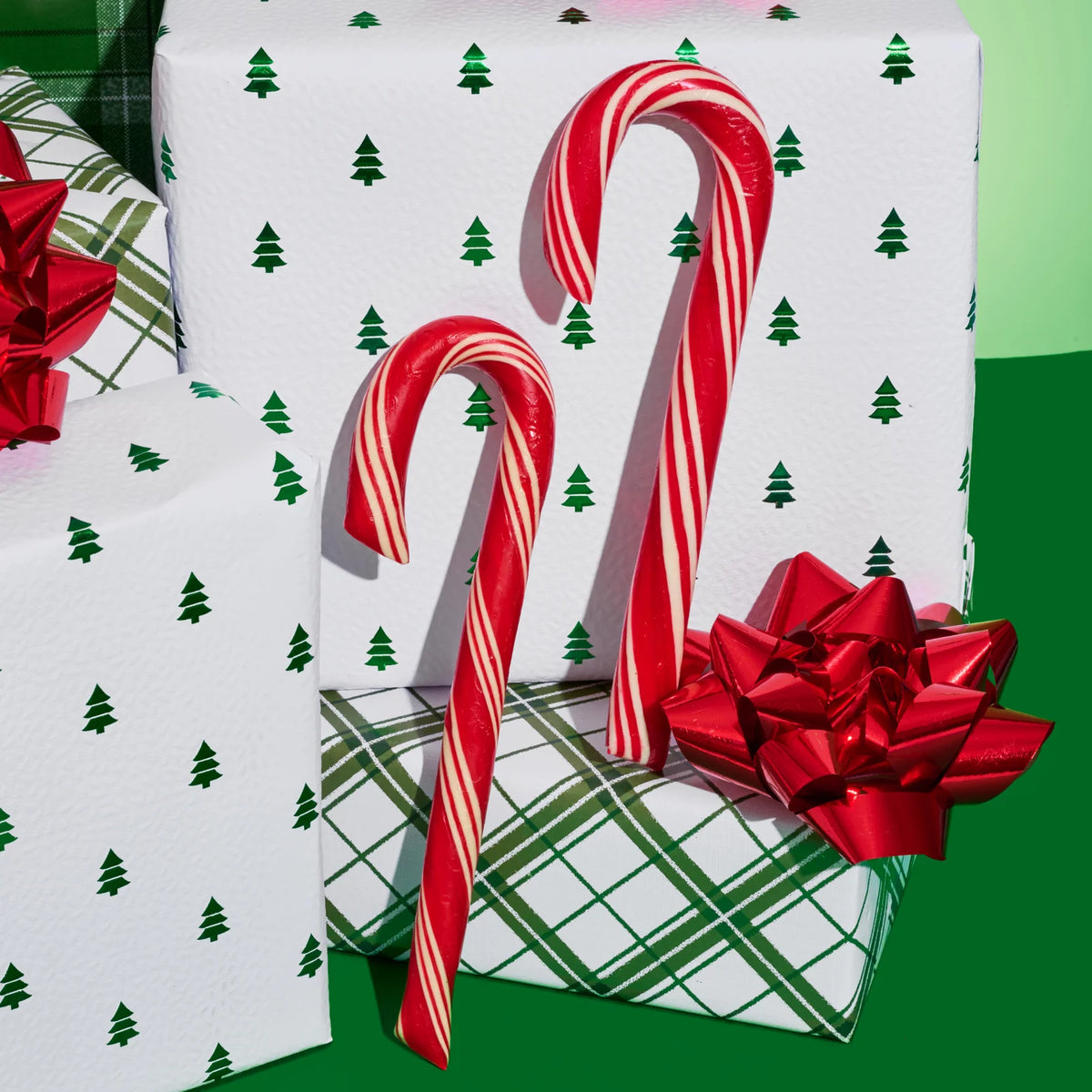 Gift boxes with candy cane design and red bows on a green background