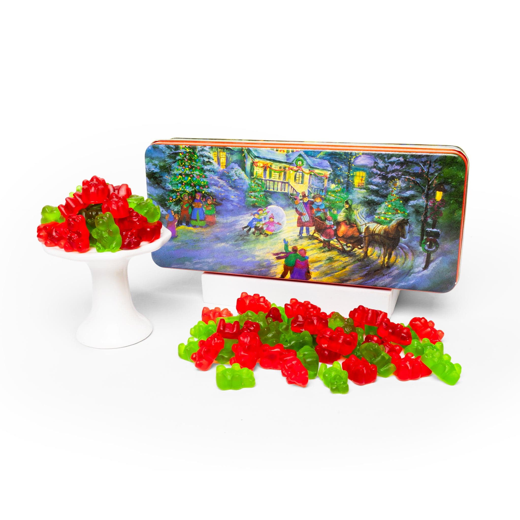Decorative tin with Christmas scene, surrounded by red and green gummy bears on a white background